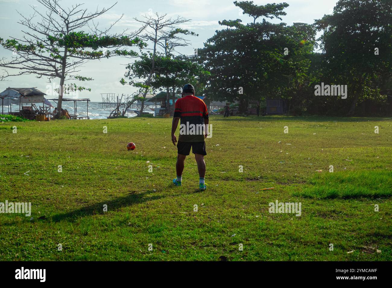 Vue arrière d’un homme qui se prépare à prendre un coup franc sur un terrain de football de Balikpapan, 17 octobre 2024, Kalimantan oriental, Indonésie Banque D'Images