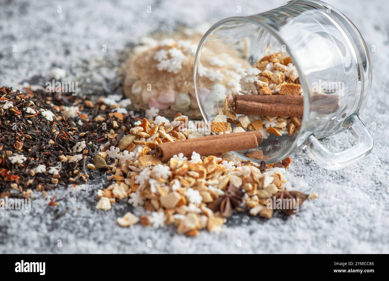 ingrédient de boisson chaude d'hiver renversé avec des épices, en forme d'étoile et de sucre et de tasse de verre retournent sur fond neigeux Banque D'Images