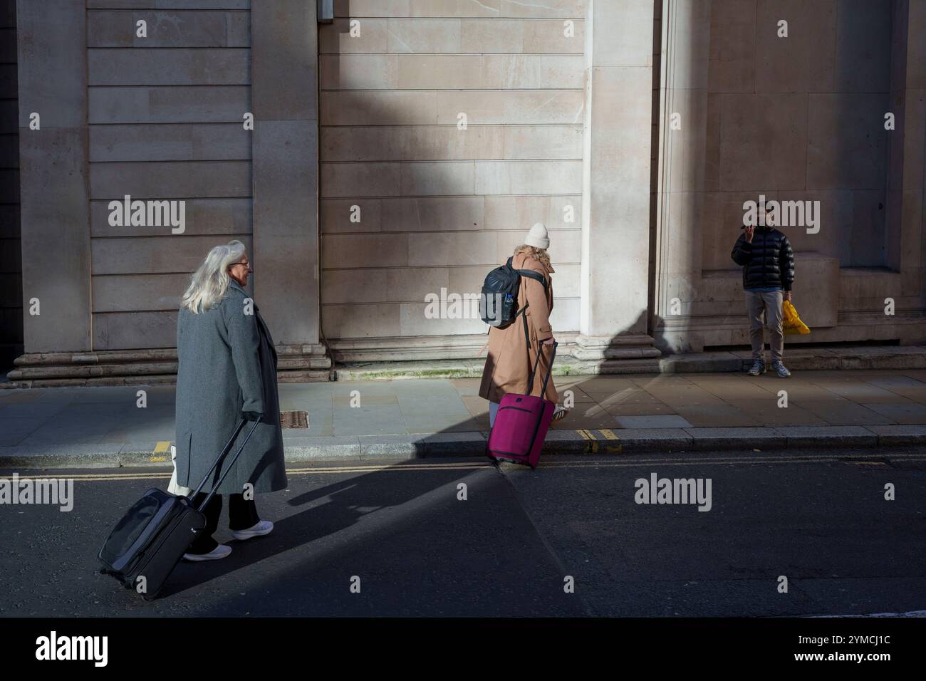 Les employés de la ville traversent l'angle de Threadneedle Street et Batholomew Lane où les murs et les colonnes de la Banque d'Angleterre sont visibles sur la droite dans la City de Londres, le quartier financier de la capitale, le 20 novembre 2024, à Londres, en Angleterre. Banque D'Images