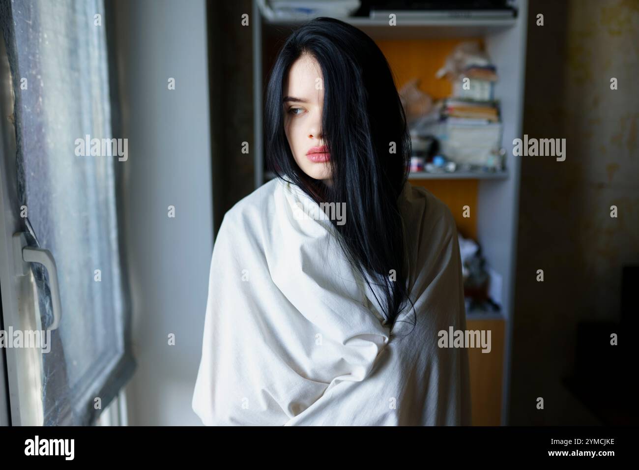 Portrait de femme pensive enveloppée dans une feuille blanche Banque D'Images