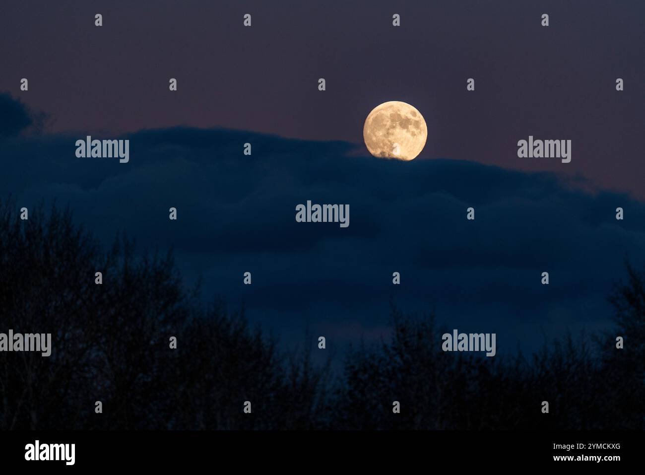 Pleine lune s'élève au-dessus de nuages Banque D'Images