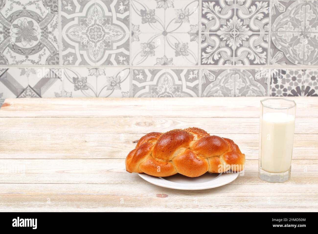 Challah fraîchement cuit servi avec un verre de lait sur une table rustique en bois Banque D'Images