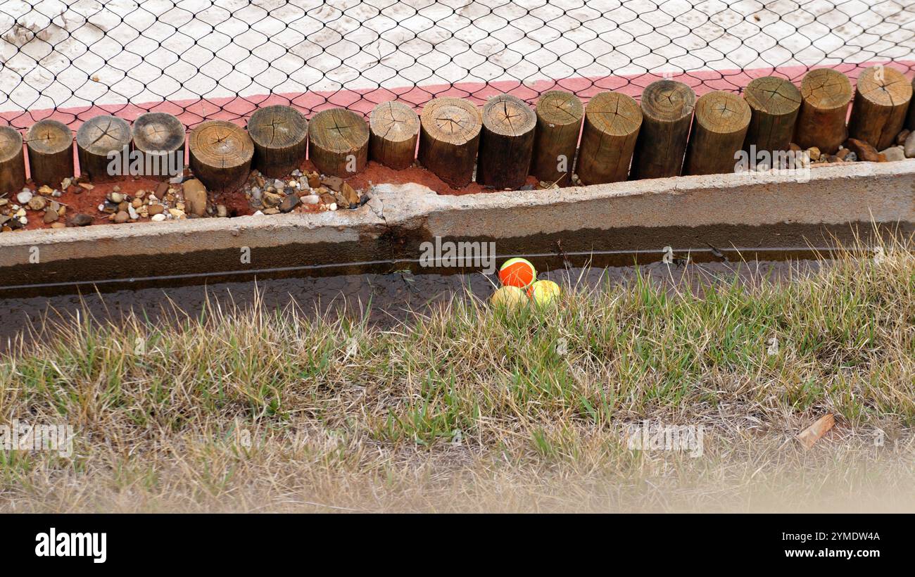 Balles utilisées dans le tennis de plage dans un canal d'eau avec des bûches en bois, de l'herbe et un filet de protection Banque D'Images