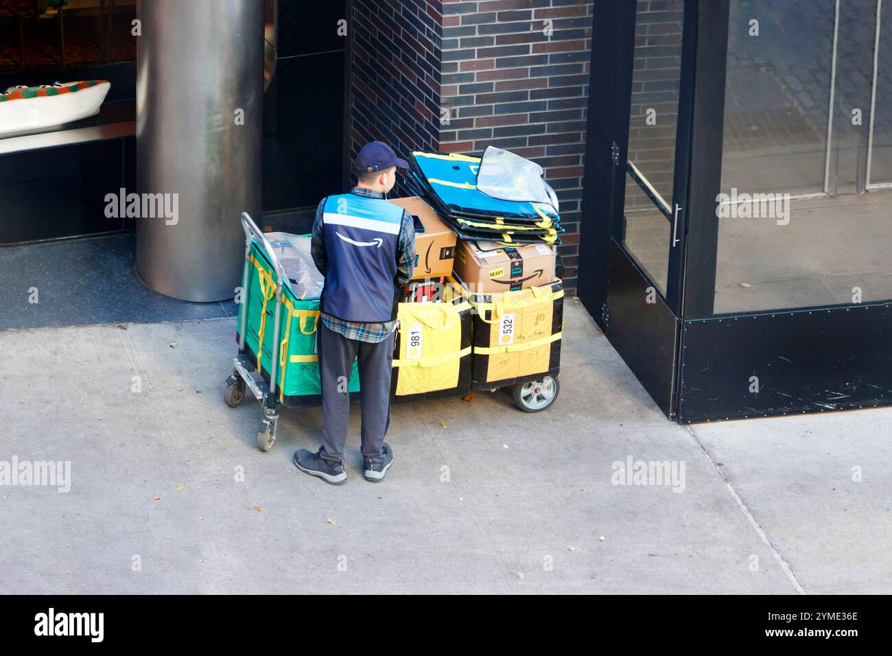 amazon Courier organise les colis de livraison sur le trottoir de la ville de Cart, à côté de l'entrée d'un immeuble de bureaux dans un cadre urbain manhattan New york Banque D'Images