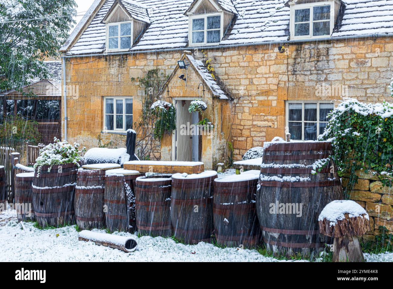 Neige du début de l'hiver tombant sur un chalet en pierre traditionnel dans le village Cotswold de Stanway, Gloucestershire, Angleterre Royaume-Uni Banque D'Images