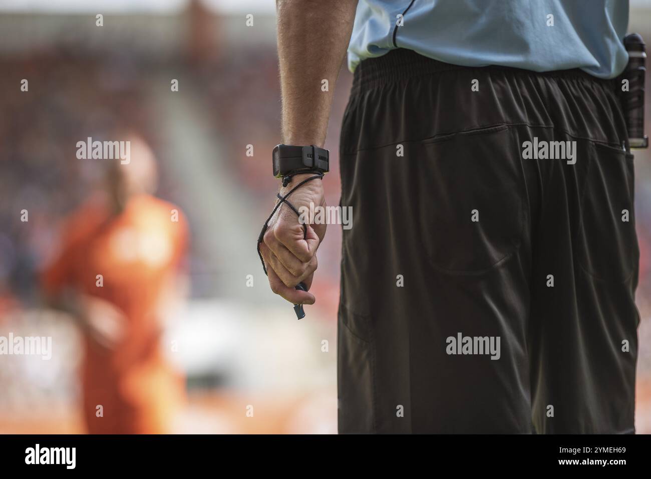 Main de l'arbitre de football avec montre-bracelet et sifflet. Banque D'Images