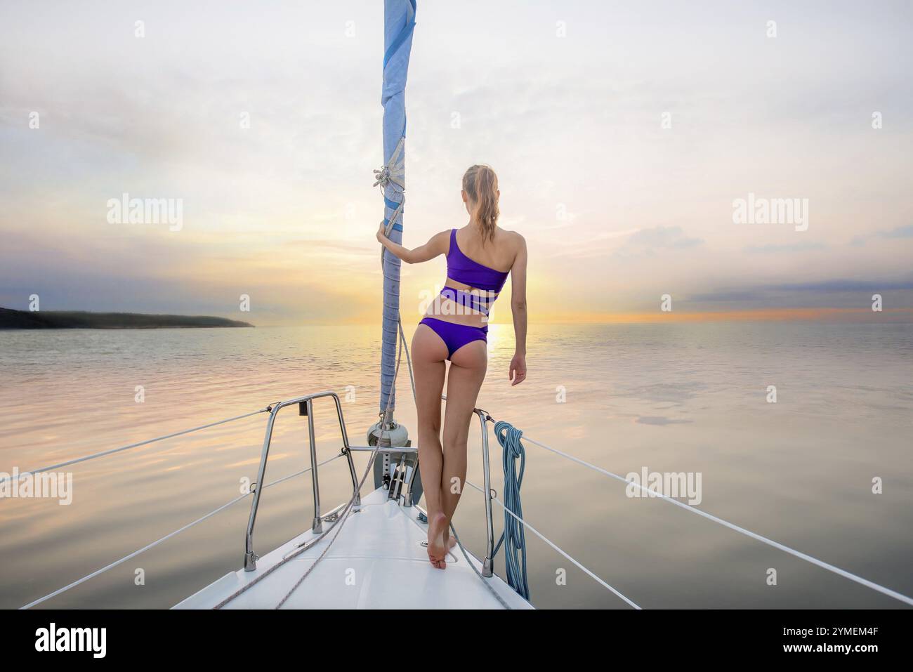 Promenade du soir sur le yacht. Fille debout sur le nez du yacht et regardant le coucher du soleil. Promenade romantique. Belle vue depuis le bateau Banque D'Images