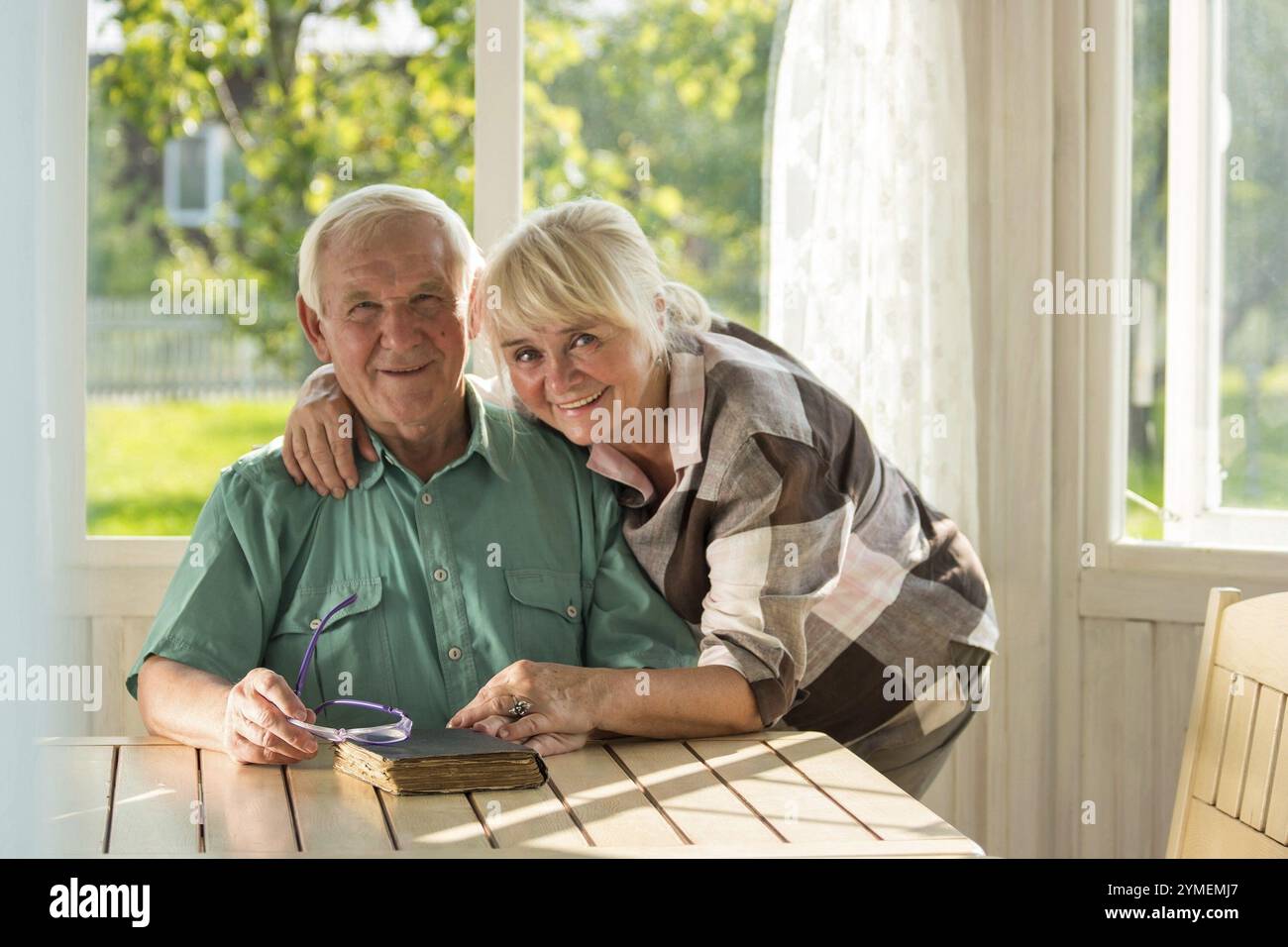 Couple senior avec un livre. Homme et femme souriant à l'intérieur. Deux vies, une histoire Banque D'Images