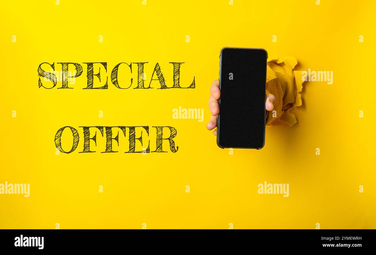 Personne tenant un téléphone cellulaire avec les mots Special Offer écrits en noir sur fond jaune. L'image a une ambiance ludique et humoristique Banque D'Images