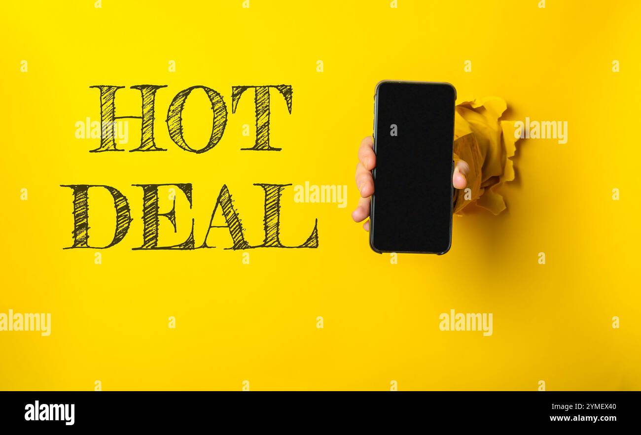 Personne tenant un téléphone avec le mot HOT DEAL écrit sur le mur derrière eux. L'image a une ambiance ludique et humoristique Banque D'Images