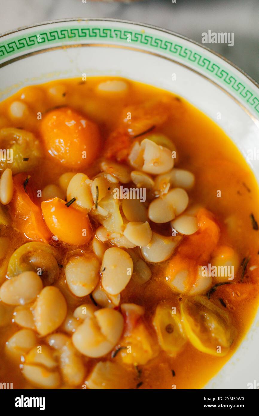 clé grecque verte sur bol de haricots beurre dans un bouillon avec tomates et romarin Banque D'Images