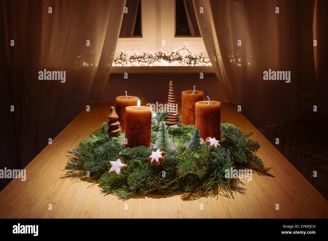 Premier Avent avec des bougies brun orange sur une couronne de l'Avent faite de branches de sapin vert et décoration de noël sur une table près de la fenêtre dans une lumière chaude, Banque D'Images