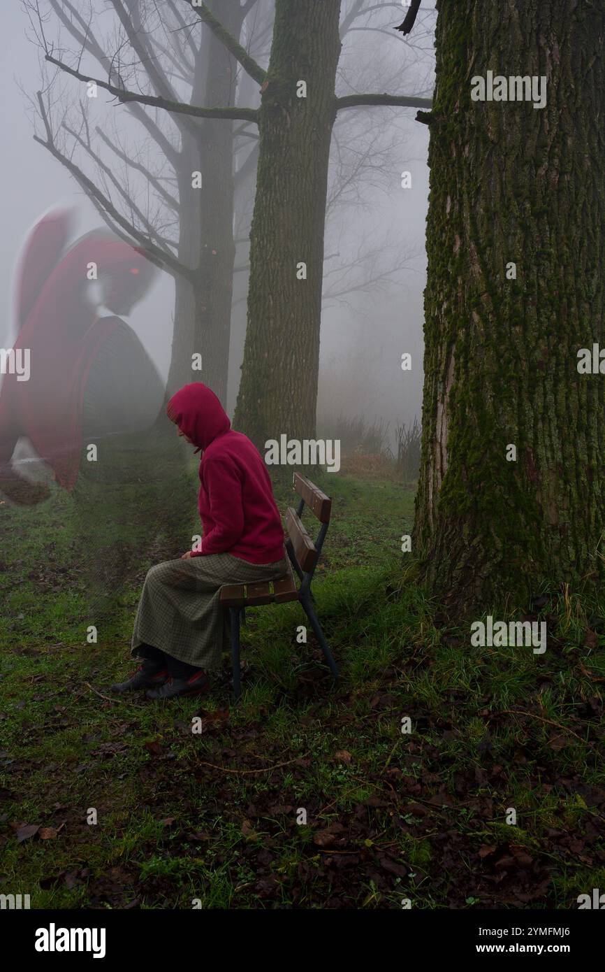 Une femme triste sur un banc de parc dans le brouillard. Un dragon qui la regarde. Banque D'Images