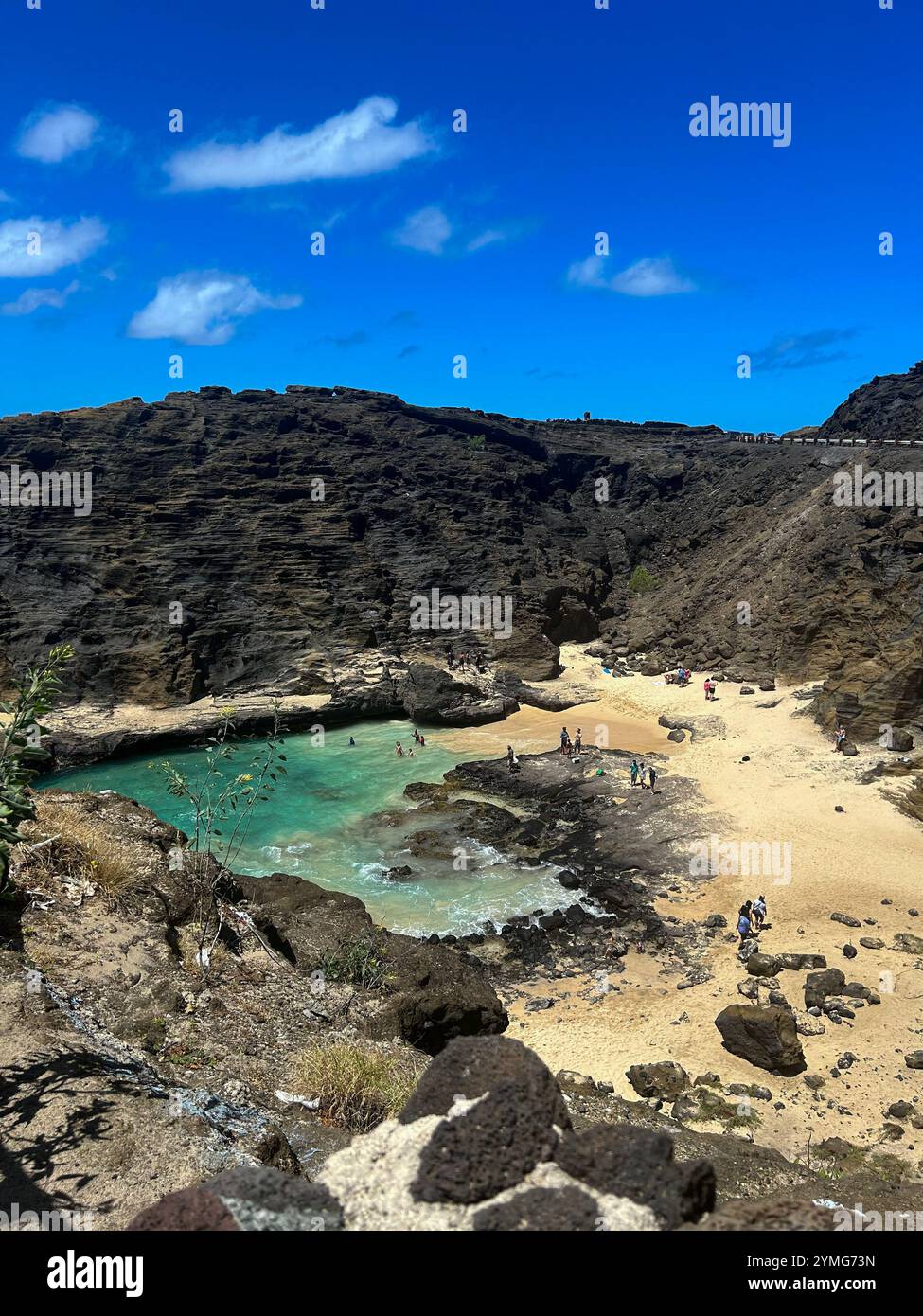 Une vue imprenable depuis une falaise surplombant une crique isolée avec une plage de sable et une eau turquoise cristalline. Les gens apprécient la plage - Image de stock capturée avec un smartphone