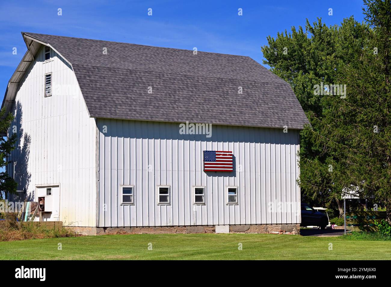 Cortland, Illinois, États-Unis. Une grange blanche bien rangée arborant un drapeau américain le long de l'un de ses côtés. Banque D'Images