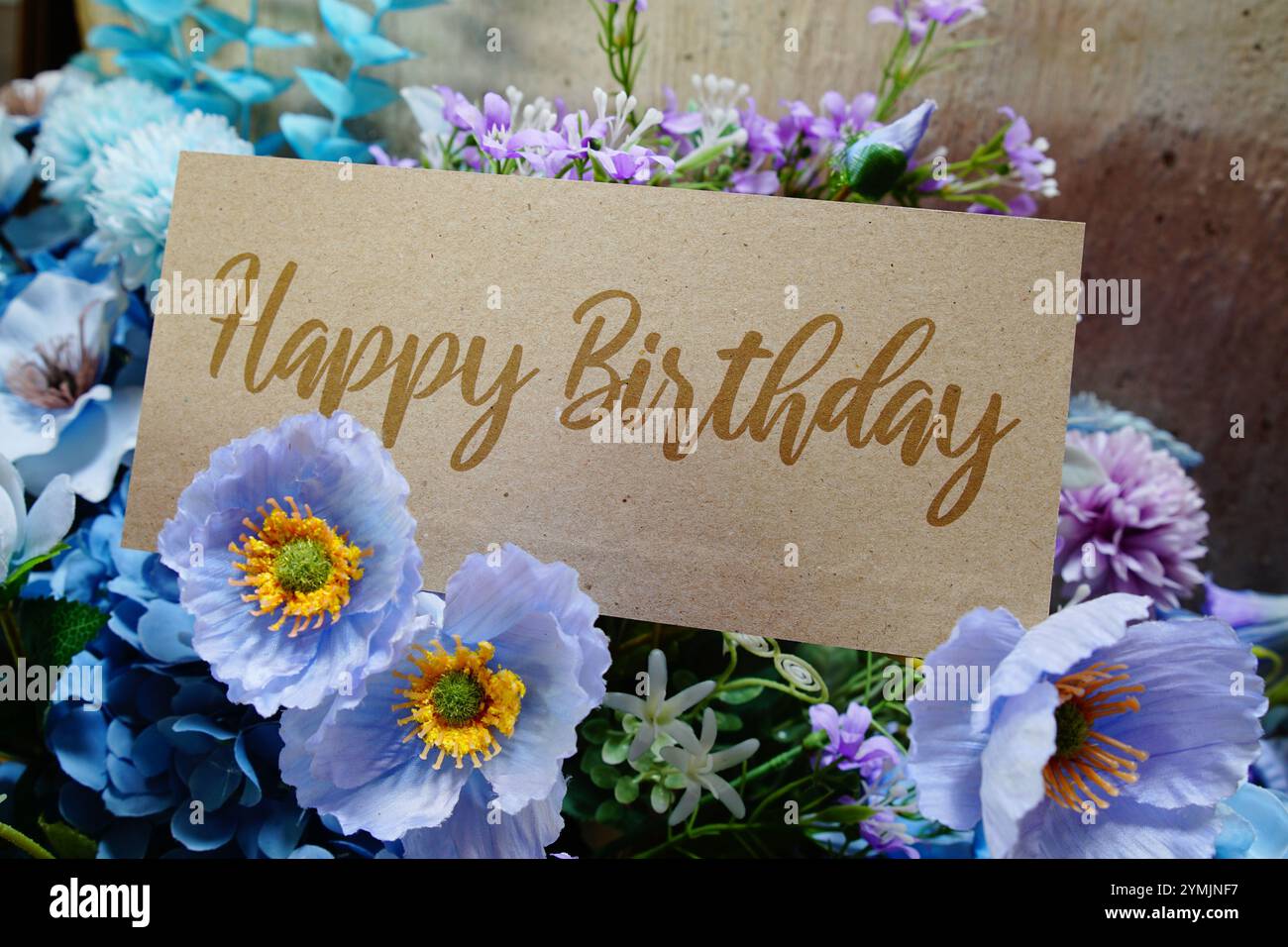 Texte joyeux anniversaire écrivez sur une carte de papier avec décoration de fleurs sur fond en bois Banque D'Images