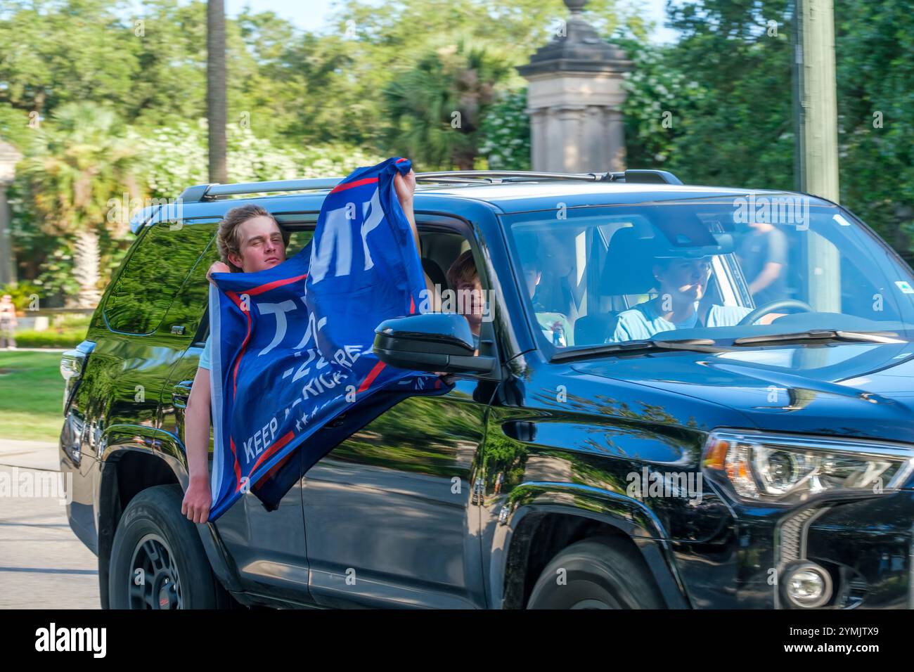 LA NOUVELLE-ORLÉANS, LOUISIANE. États-Unis - 24 JUIN 2024 : de jeunes adolescents avec le drapeau Trump manifestent depuis un véhicule en mouvement à l'extérieur d'Audubon place, une communauté fermée sur l'avenue Charles où Trump organise une collecte de fonds. Les adolescents encerclaient le bloc et traînaient des manifestants anti-atouts. Le cortège de Trump n'était pas encore arrivé pour la collecte de fonds. Banque D'Images