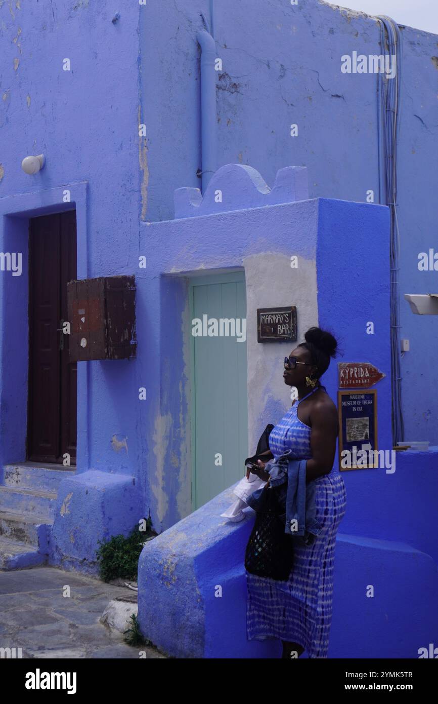 Femme en bleu devant un bâtiment bleu à Oia, Santorin Banque D'Images