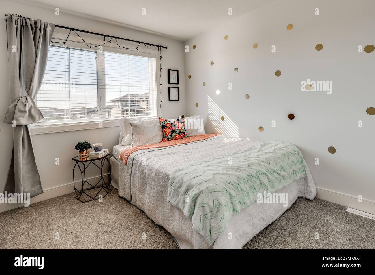 Une chambre avec un lit blanc et une couette verte et blanche. Le lit est entouré d'une fenêtre et d'une table Banque D'Images