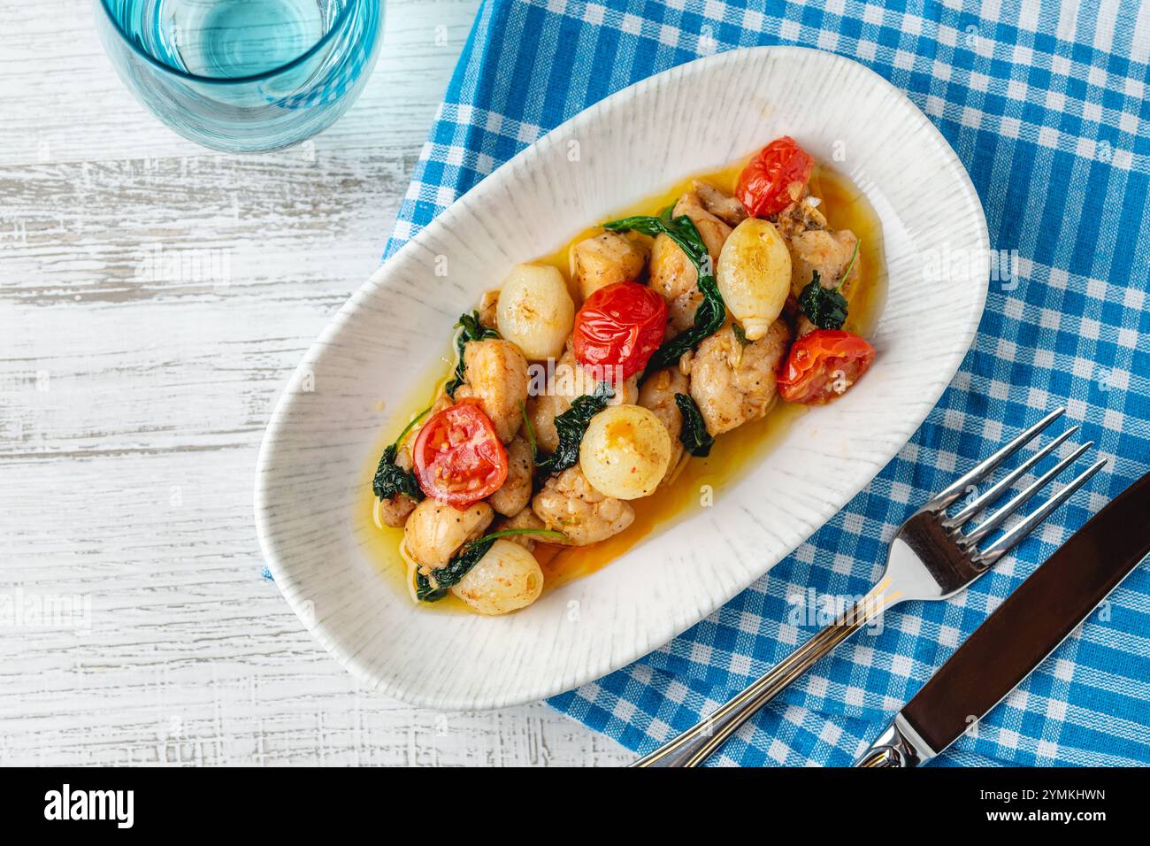 Apéritif avec des crevettes, des oignons et des tomates sur une assiette en porcelaine blanche Banque D'Images