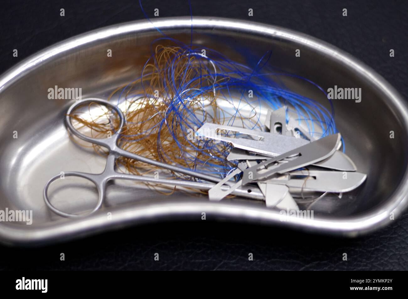 Lames de scalpel, suture chirurgicale, point de suture, points de suture avec une pince dans un petit bocal de rein en acier inoxydable, les sutures sont des dispositifs médicaux utilisés pour tenir le corps Banque D'Images