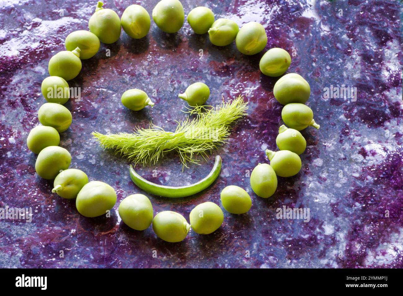 symbole de sourire fait par des pois frais et fenouil sauvage, fond de couleur pierre violette Banque D'Images