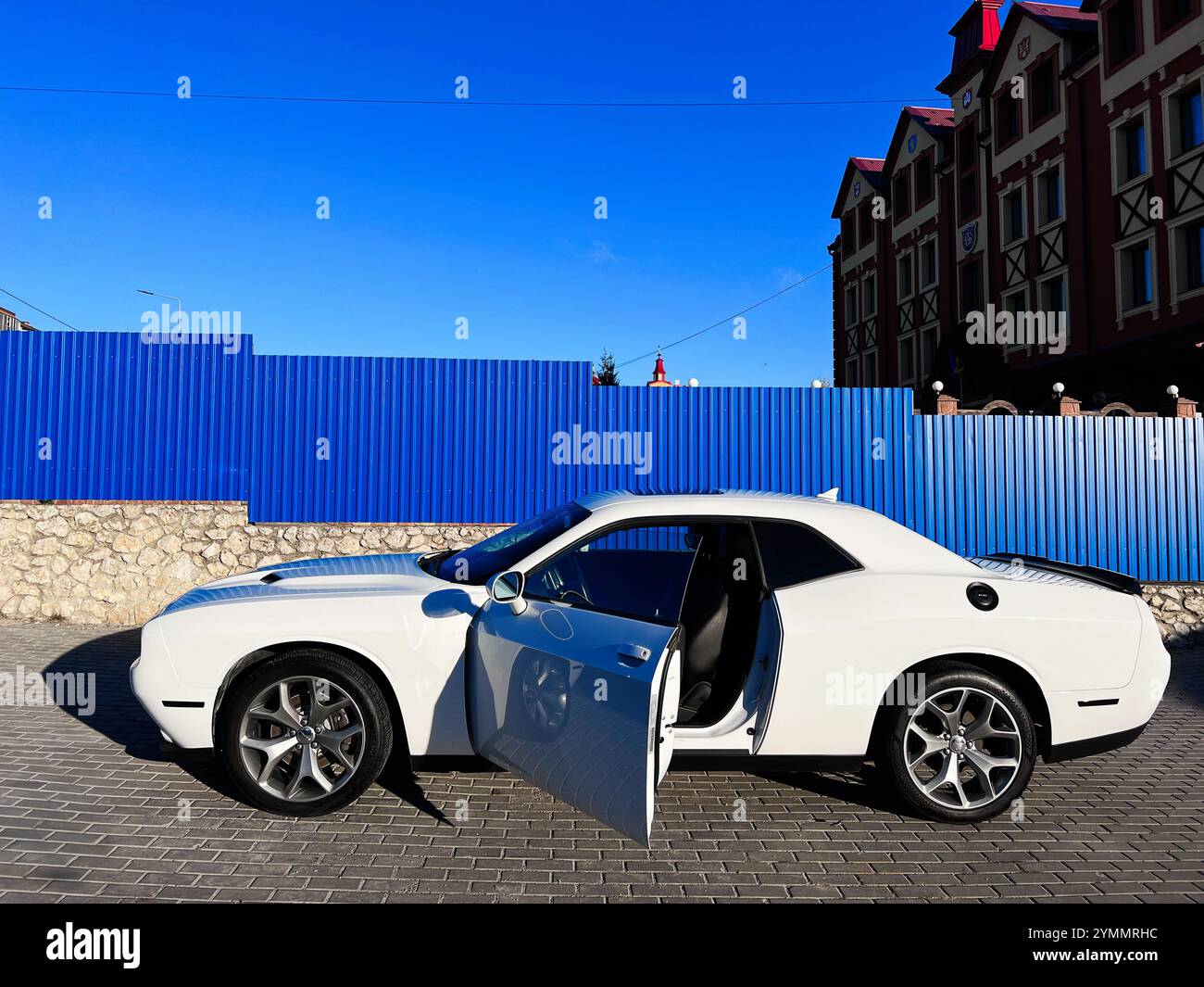 Kiev, Ukraine - 22 novembre 2024 : une voiture blanche moderne Dodge Challenger avec une porte ouverte est garée dans une rue de la ville, mettant en valeur l'architecture urbaine et Banque D'Images