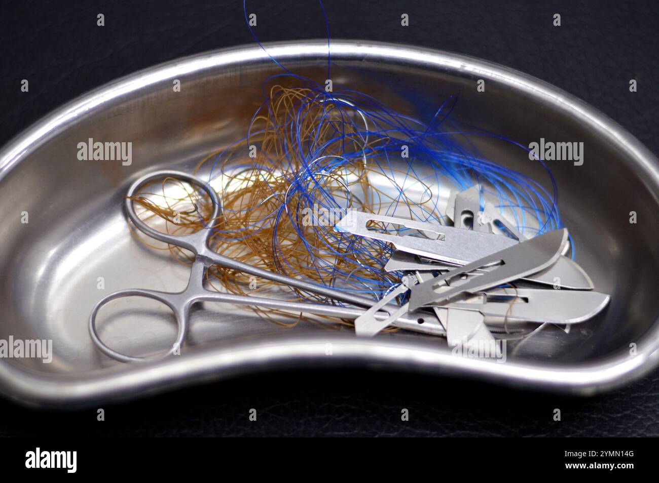Lames de scalpel, suture chirurgicale, point de suture, points de suture avec une pince dans un petit bocal de rein en acier inoxydable, les sutures sont des dispositifs médicaux utilisés pour tenir le corps Banque D'Images