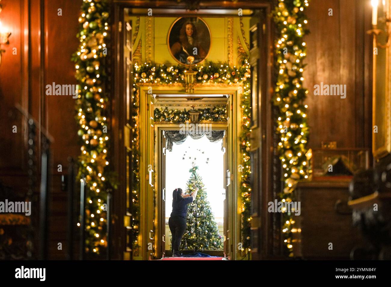 Chef de la fête, Val Goldman, met la touche finale aux arbres de Noël dans le Boudoir bleu du château de Warwick. Une équipe de 35 experts en histoire, costumes et paysages passe 750 heures à planifier et quatre semaines à installer des lumières, des décorations et des arbres avant la saison des fêtes. Il faut 100 heures pour décorer l'intérieur du château, et encore 40 heures dans le parc pour accrocher environ 50 000 lumières de Noël, décorer 30 arbres de Noël autour et poser la traînée lumineuse de 1 680 mètres. Date de la photo : vendredi 22 novembre 2024. Banque D'Images