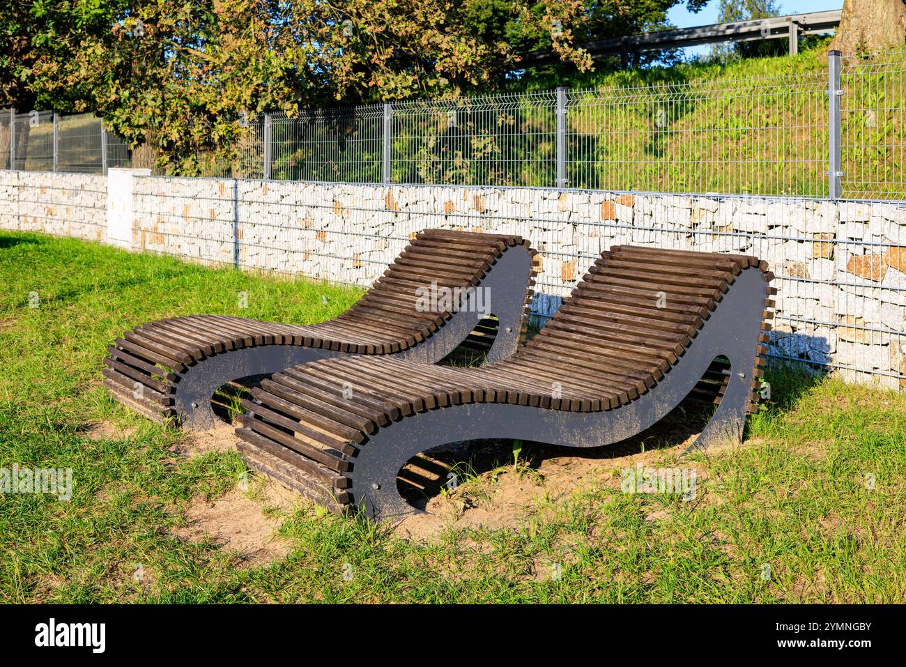 Deux chaises longues stationnaires sur une plage de la ville. Pelouse verte et gabion en arrière-plan. Banque D'Images