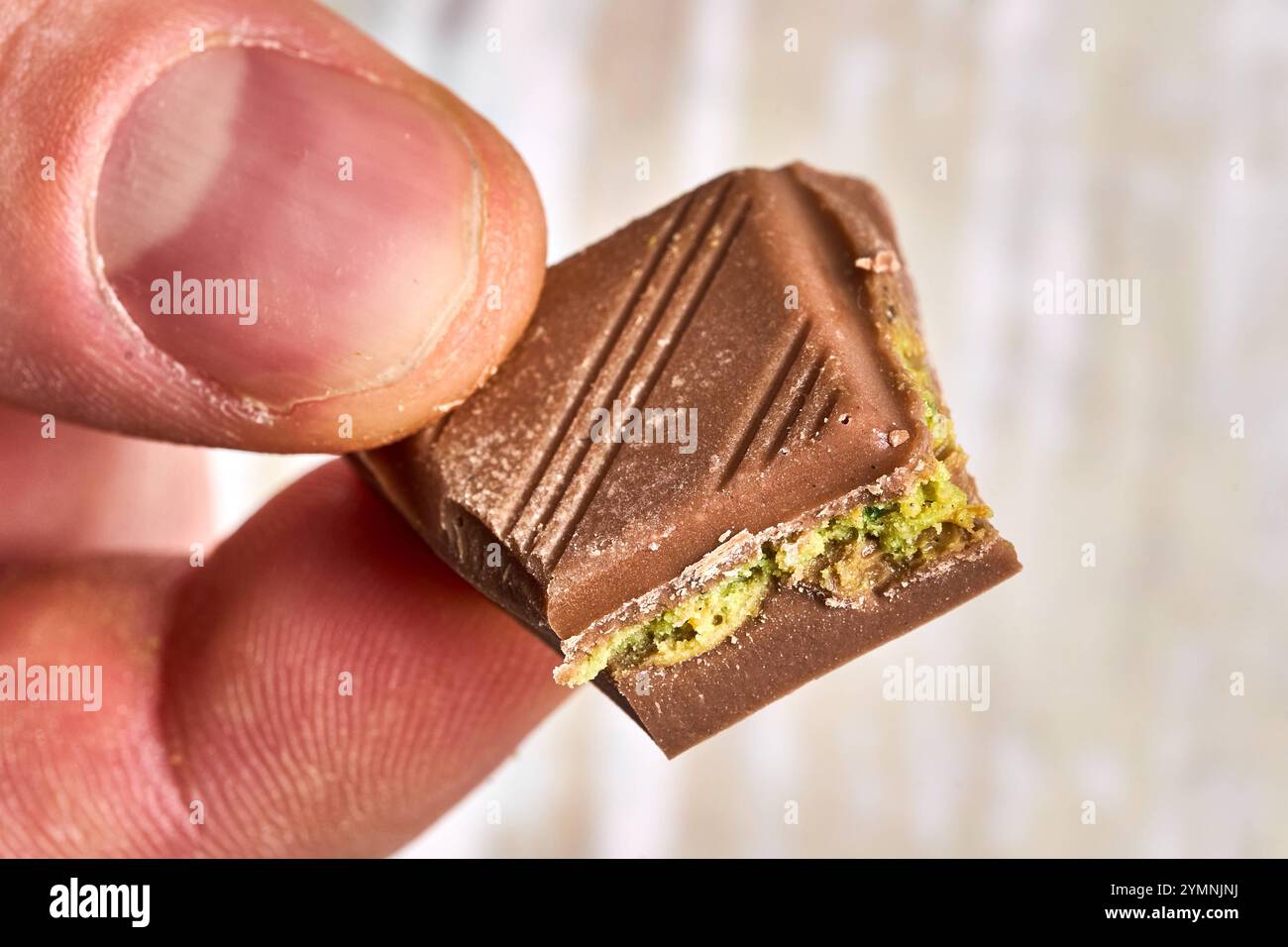 Bavière, Allemagne - 22 novembre 2024 : un homme tient une seule pièce du luxueux chocolat de Dubaï, avec des pistaches et un soupçon de KadayÄf pour son goût unique *** Ein Mann hält ein einzelnes Stück der luxuriösen Dubai Schokolade in der hand, die mit Pistazien und einem Hauch von KadayÄf für ihren einzigartigen Geschmack steht Banque D'Images