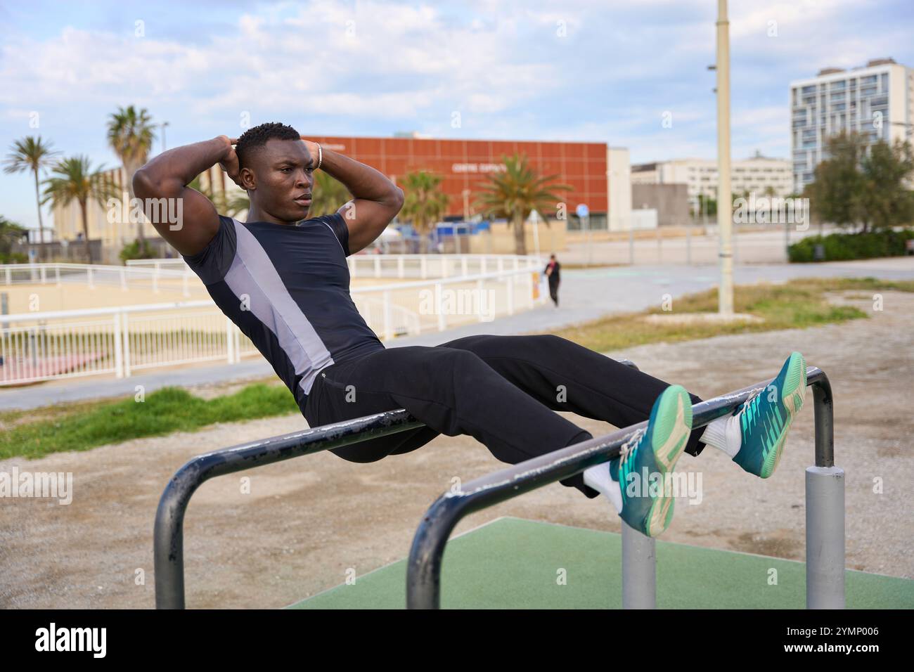 Jeune homme noir effectuant des sit-ups calisthéniques dans un parc urbain Banque D'Images
