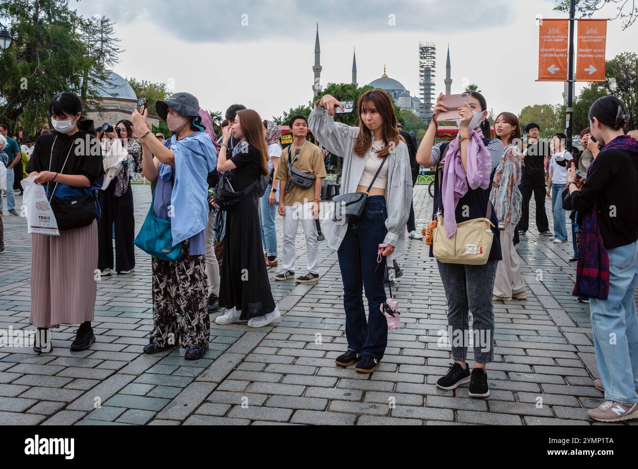 Touristes japonais prenant des photos dans le parc Sultanahmet avec la Mosquée bleue (Sultanahmet Camii) en arrière-plan, Istanbul, Turquie Banque D'Images Touristes japonais prenant des photos dans le parc Sultanahmet avec la Mosquée bleue (Sultanahmet Camii) en arrière-plan, Istanbul, Turquie Banque D'Images