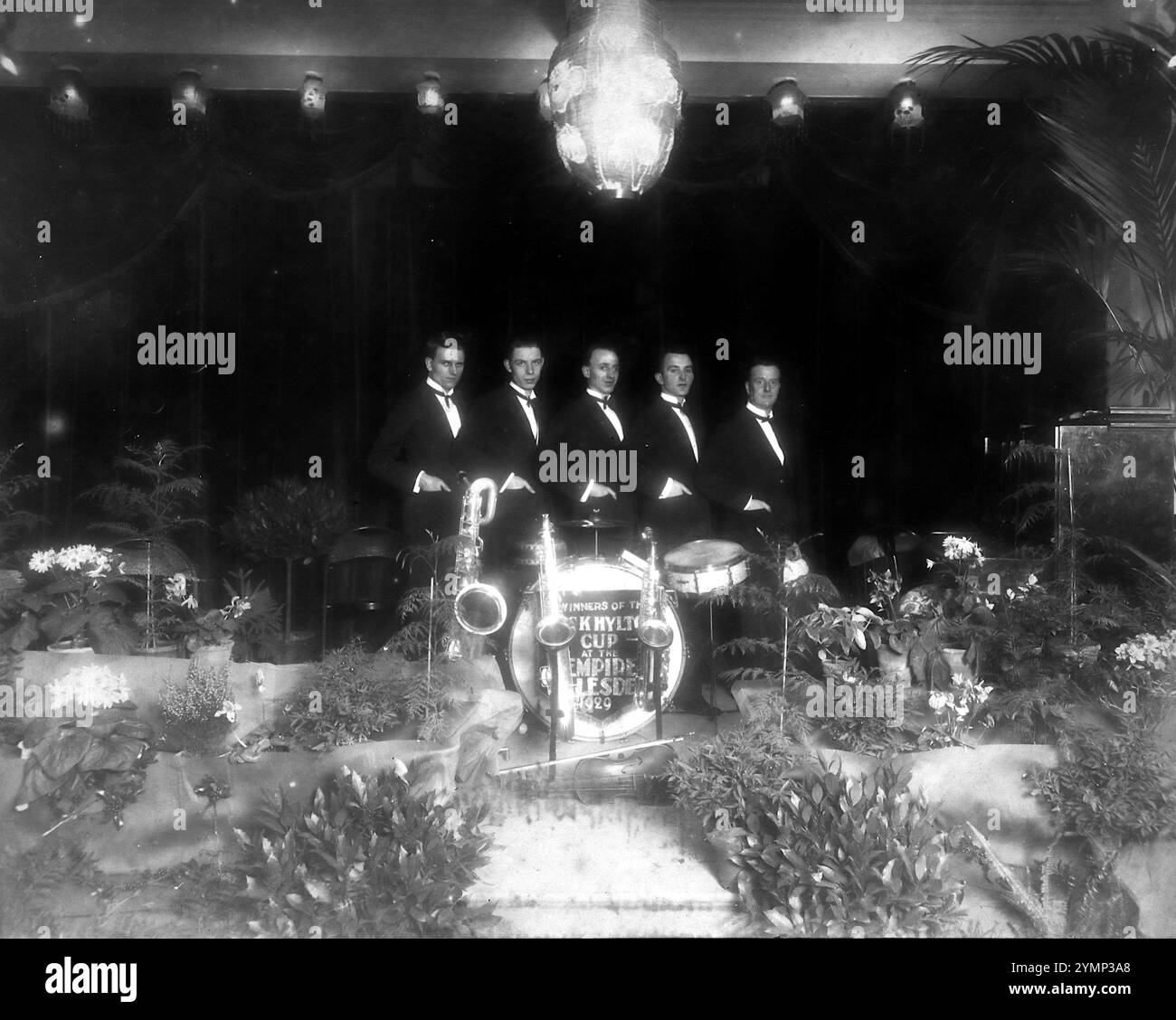 Photographie, c1929, peut-être un groupe de jazz de cinq membres lors d'une cérémonie de remise des prix. Il y a cinq messieurs alignés derrière des instruments. Un panneau sur le tambour de base est partiellement visible : 'vainqueurs de la 'Something Hylton Cup, à l'Empire...' La ligne suivante n'est pas claire mais semble être Hillesden ou Willesden, d'où probablement le Willesden Empire Theatre à Hillesden, Londres. Banque D'Images