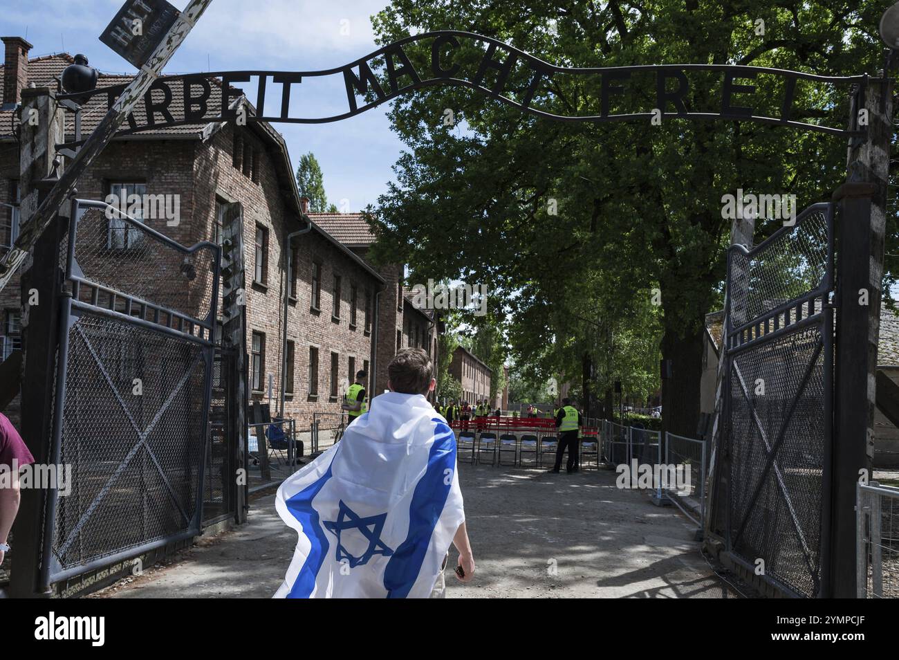 Jude avec le drapeau israélien dans le camp de concentration nazi allemand Auschwitz Birkenau. Écriture sur la porte d'entrée en allemand Arbeit Mach frei Banque D'Images