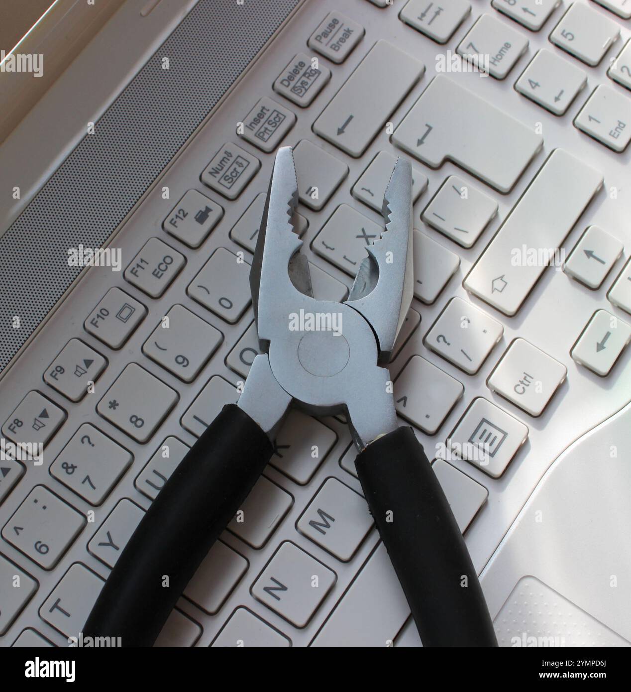 Image du concept de support PC. Pinces métalliques sur clavier d'ordinateur portable vue rapprochée. Boutons blancs du clavier d'ordinateur portable avec pinces mécaniques dessus Banque D'Images