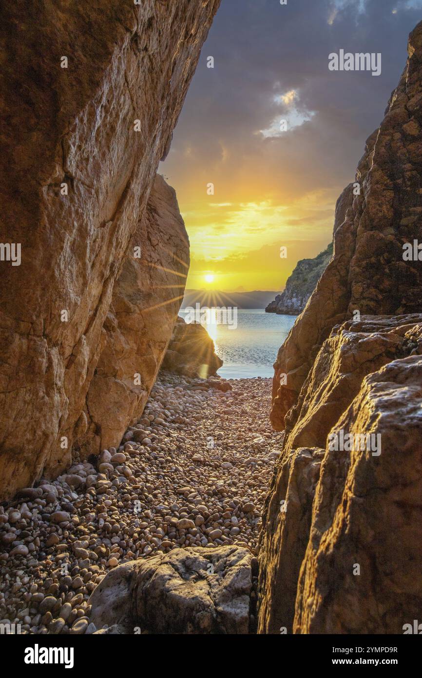 Baie cachée et plage avec un vieux village de montagne. Le lever du soleil se reflète dans l'eau. Un beau paysage photographié encadré par les falaises et l'Adriatique Banque D'Images