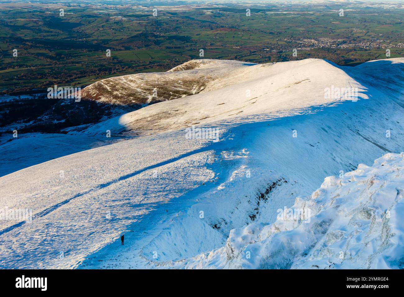 Randonneur solitaire descendant une crête de montagne enneigée en fin d'après-midi Banque D'Images