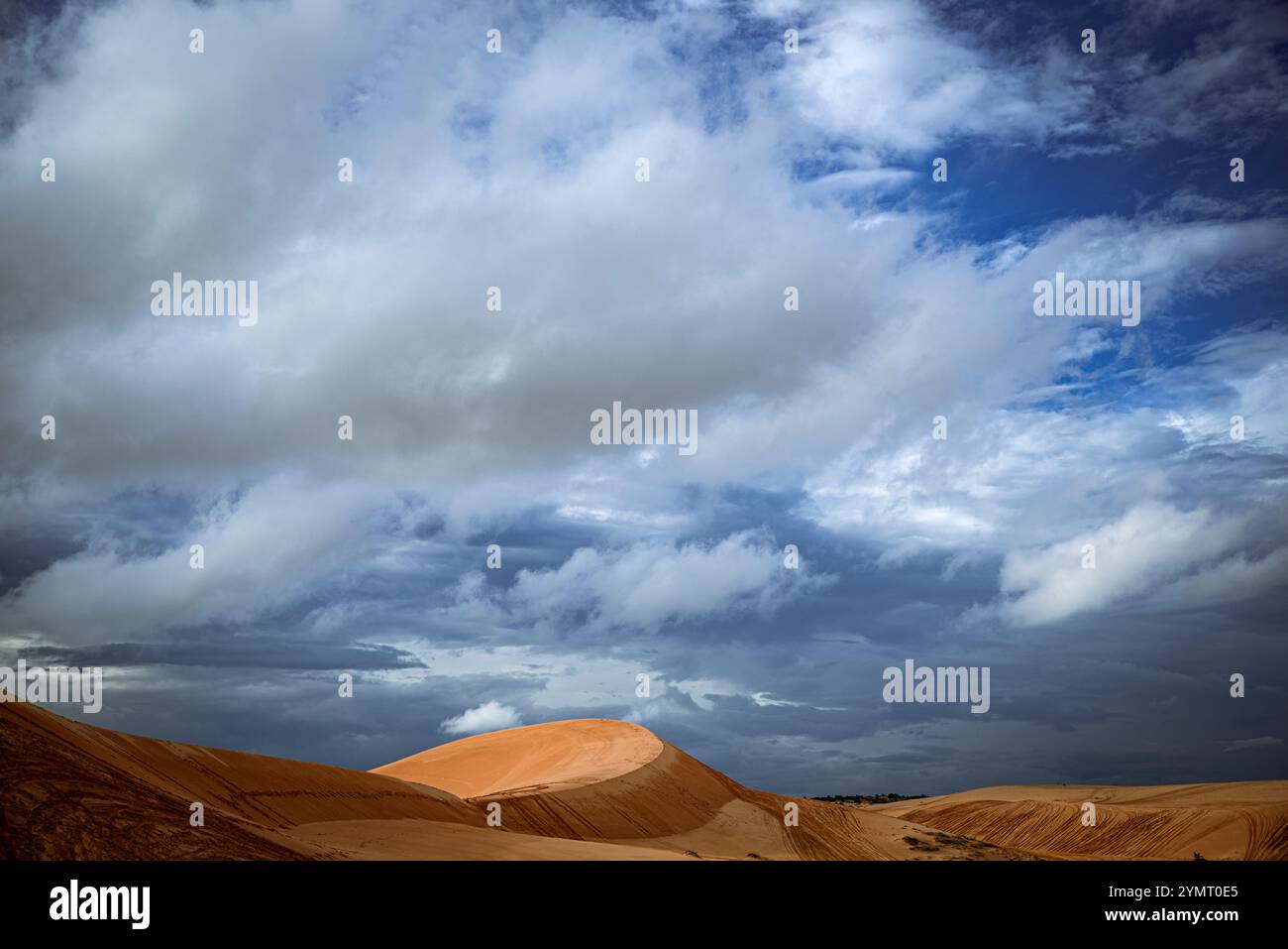 Un paysage désertique avec une colline et un ciel nuageux. Le ciel est principalement nuageux avec quelques taches de bleu Banque D'Images