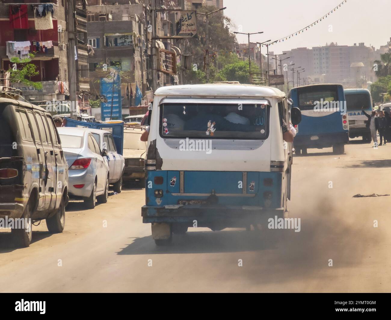Une camionnette bleue et blanche descend une rue avec beaucoup de circulation. La camionnette crache de la fumée de son échappement Banque D'Images