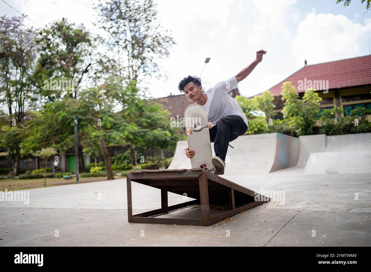 Un skateur expérimenté effectue un tour impressionnant sur une rampe dans un skate Park animé et dynamique Banque D'Images