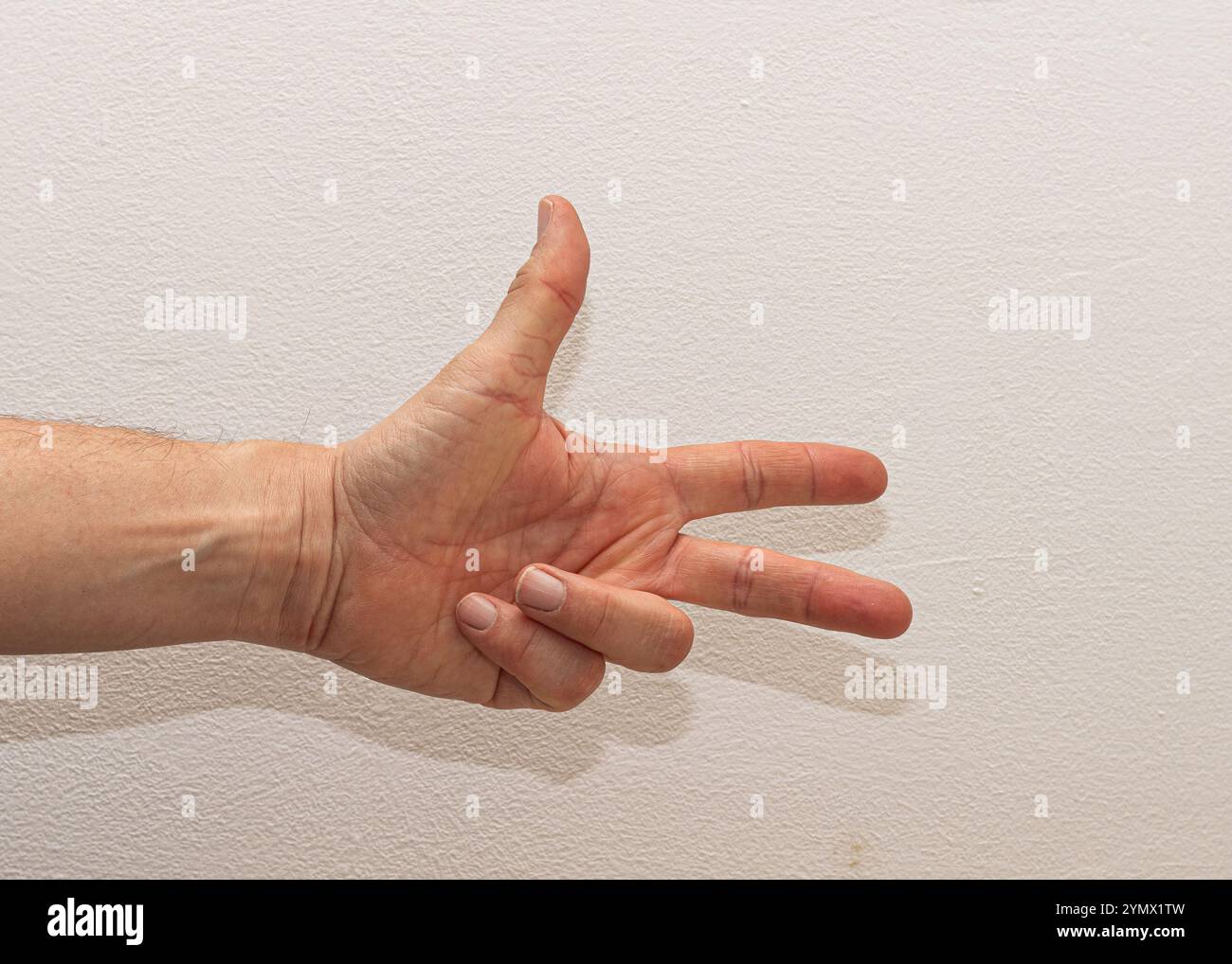 Gros plan de la main d'un homme caucasien affichant le numéro trois en tenant trois doigts sur un fond blanc Uni Banque D'Images