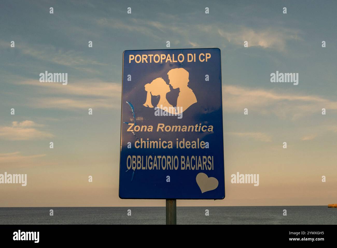 Un panneau disant 'baiser ici - emplacement pour des photos romantiques' surplombant la mer Méditerranée dans la petite ville côtière de Portopalo di Capo Passero. Banque D'Images