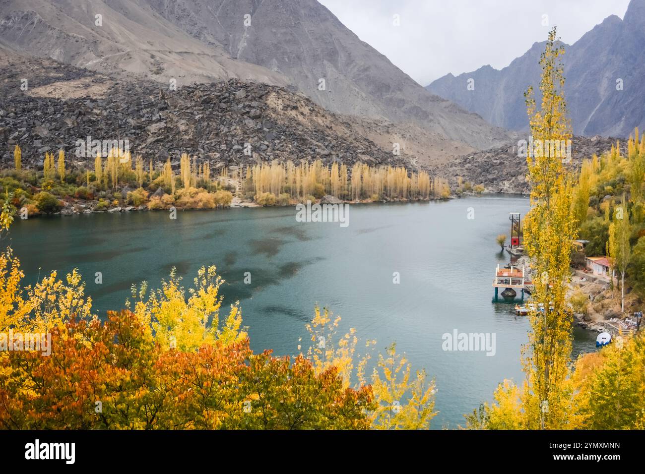 Des arbres dorés d'automne encerclent le lac gelé de Skardu, leurs reflets scintillant sur la surface glacée Banque D'Images