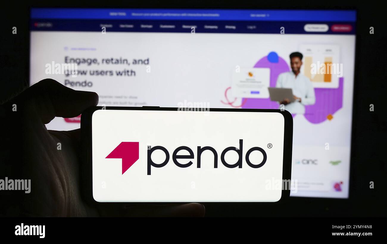 Stuttgart, Allemagne, 07-11-2024 : personne tenant un téléphone portable avec le logo de la société américaine de logiciels Pendo.io Inc. devant la page Web de l'entreprise. Mise au point Banque D'Images