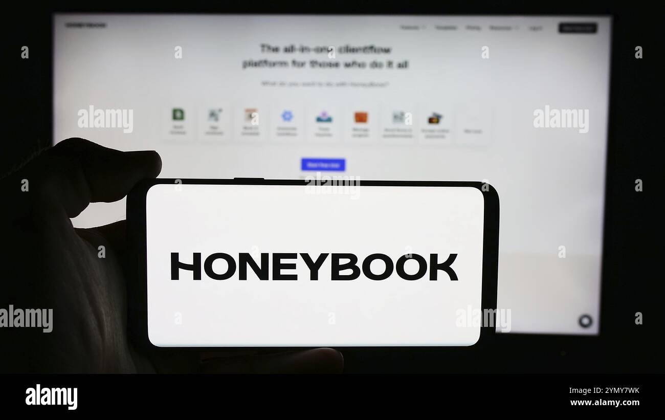 Stuttgart, Allemagne, 07-14-2024 : personne tenant un téléphone portable avec le logo de la société américaine de gestion du flux de clientèle HoneyBook Inc en face de la page Web de l'entreprise. FO Banque D'Images