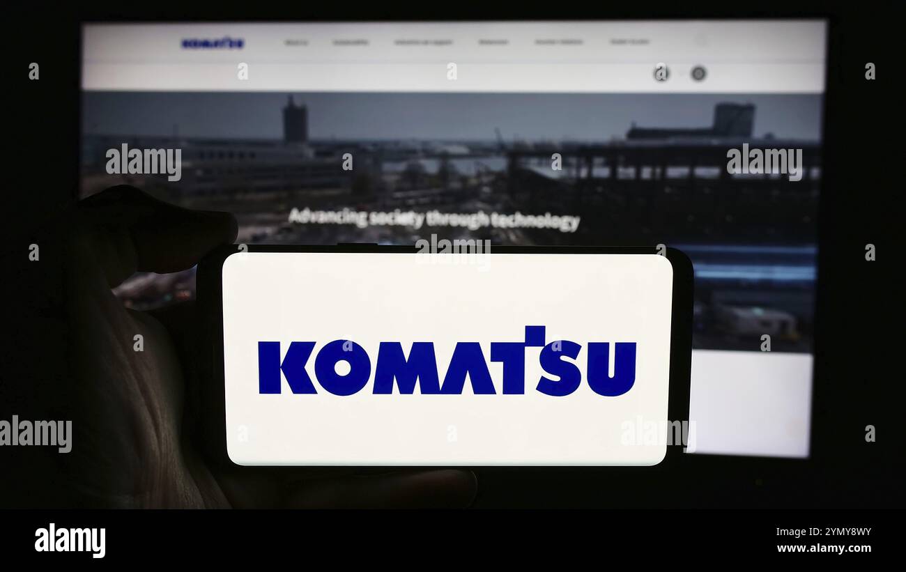 Stuttgart, Allemagne, 07-25-2024, personne tenant un téléphone portable avec le logo de la société japonaise d'équipement lourd Komatsu Ltd en face de la page Web de l'entreprise. Focu Banque D'Images