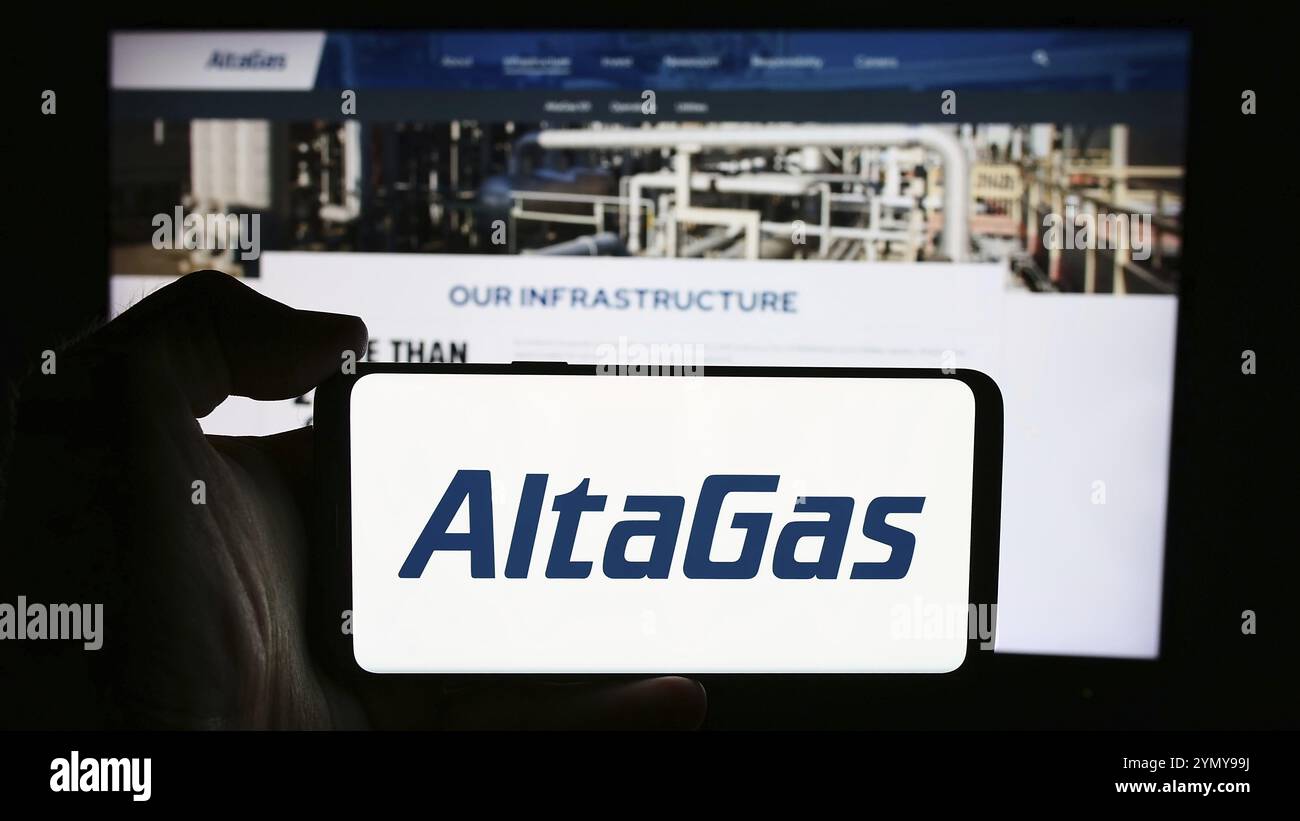 Stuttgart, Allemagne, 07-16-2024 : personne tenant un téléphone cellulaire avec le logo de la société canadienne d'infrastructure énergétique AltaGas Ltd. Devant la page Web de l'entreprise Banque D'Images