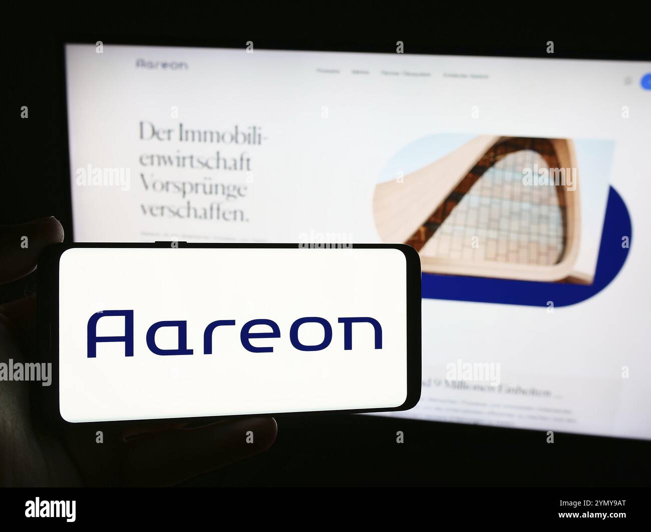 Stuttgart, Allemagne, 07-21-07 2024 : personne tenant un smartphone avec le logo de la société allemande de logiciels immobiliers Aareon AG en face du site Web. Concentrez-vous sur pho Banque D'Images
