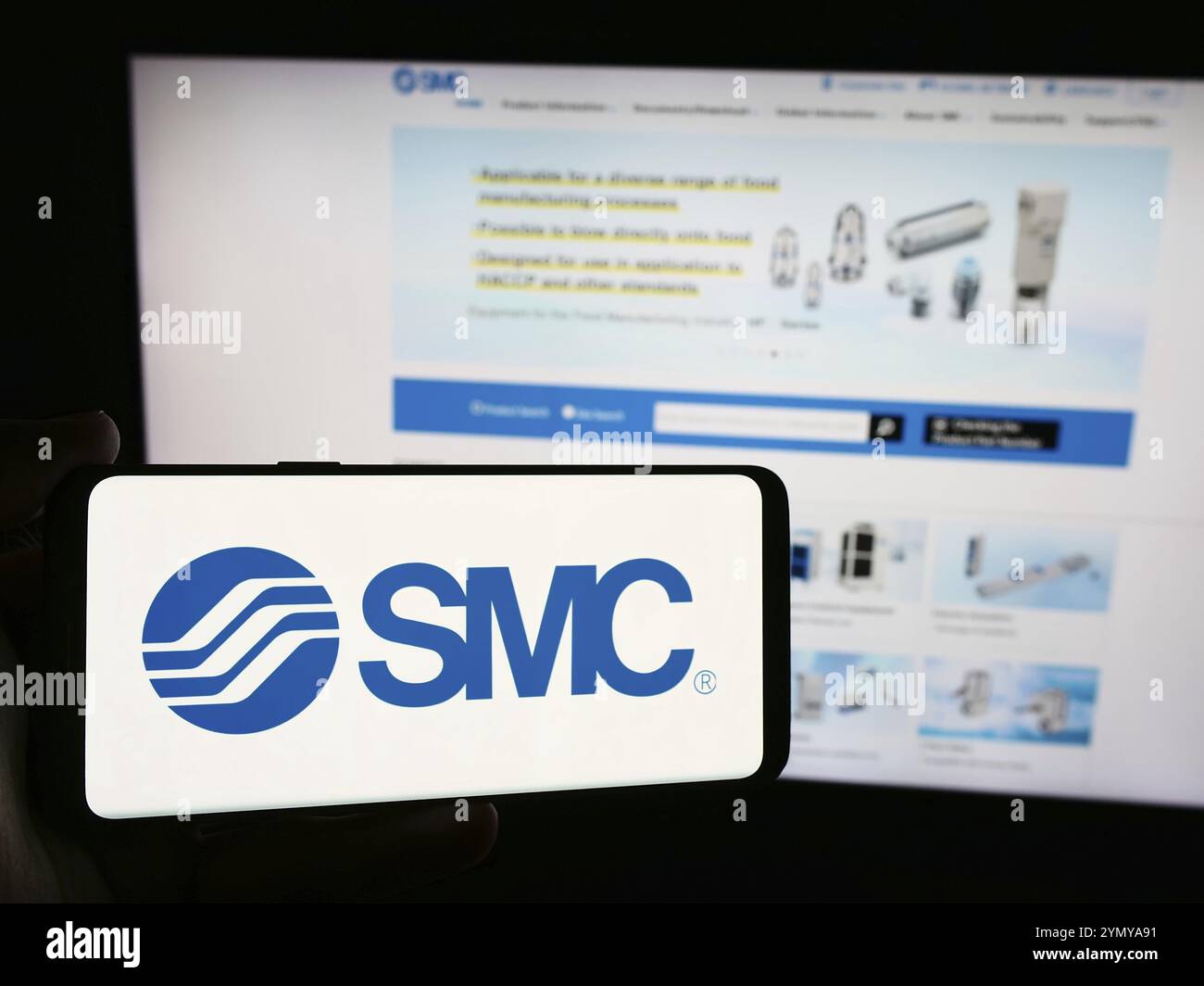 Stuttgart, Allemagne, 07-25-2024, personne tenant un smartphone avec le logo de la société japonaise de machines SMC Corporation devant le site Web. Concentrez-vous sur le téléphone Banque D'Images